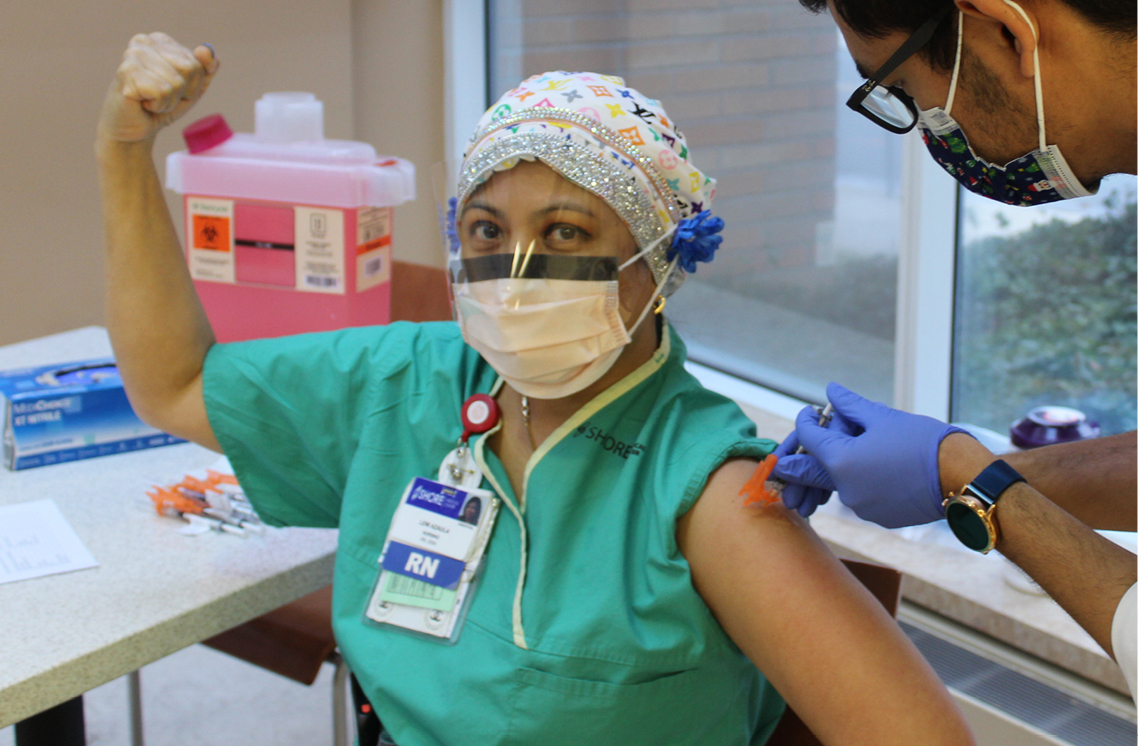 Male healthcare worker administering vaccine to a female patient.